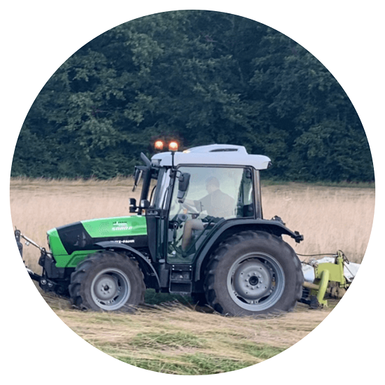 Tracteur dans un champs qui fauche l'herbe pour faire les foins
